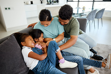 Image showing Happy, laugh and play family smile in the lounge at home. Mother, father and young children playing, having fun and bonding. Parents teasing, joking and tickling their adorable and cute kids