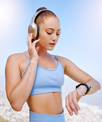 Image showing Fitness, runner and woman on time by her smartwatch as she monitors her performance, heartbeat and pulse outdoors. Headphones, health and girl running in summer streaming music, radio song or podcast