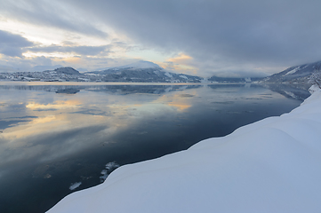 Image showing Tranquil Winter Evening Overlooking a Calm Snow-Covered Fjord Wi