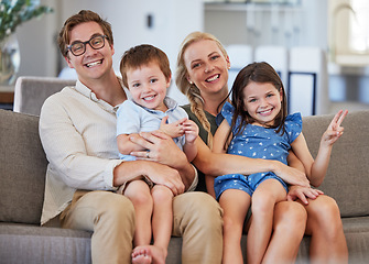 Image showing Family, smile and love of children on lap of mom and dad sitting on the sofa at home for bonding, fun and joy. Man, woman and boy and girl kids sitting together for leisure and showing peace sign