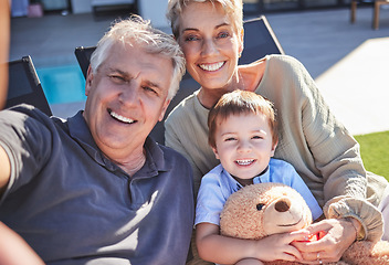 Image showing Grandparents, boy and backyard selfie in home on lawn chairs on grass sharing love, energy and bonding. Portrait of retired happy man, woman and kid with teddy, caring and enjoying time together.