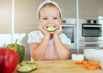 Image showing Cute girl with a smile eating cucumber, cooks healthy green salad for a meal and learning about nutrition benefits. Fresh fruit, organic vegetables and natural food is important for child development
