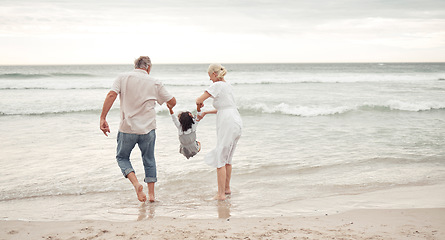 Image showing Family, children and beach with a girl and her grandparents by the sea or ocean in nature. Sand, water and summer with a senior man, woman and their granddaughter on holiday or vacation by the coast