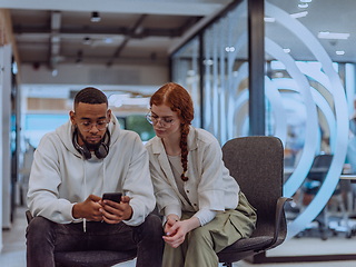 Image showing In a modern office African American young businessman and his businesswoman colleague, with her striking orange hair, engage in collaborative problem-solving sessions