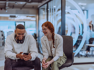 Image showing In a modern office African American young businessman and his businesswoman colleague, with her striking orange hair, engage in collaborative problem-solving sessions