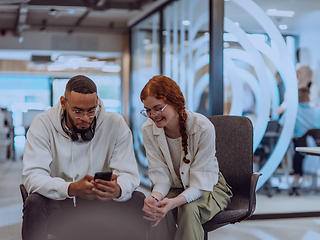 Image showing In a modern office African American young businessman and his businesswoman colleague, with her striking orange hair, engage in collaborative problem-solving sessions