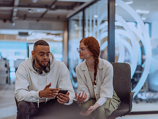 Image showing In a modern office African American young businessman and his businesswoman colleague, with her striking orange hair, engage in collaborative problem-solving sessions