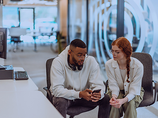 Image showing In a modern office African American young businessman and his businesswoman colleague, with her striking orange hair, engage in collaborative problem-solving sessions