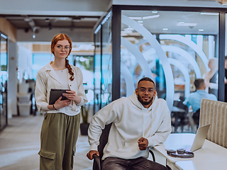 Image showing In a modern office African American young businessman and his businesswoman colleague, with her striking orange hair, engage in collaborative problem-solving sessions