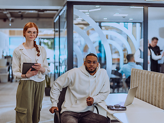 Image showing In a modern office African American young businessman and his businesswoman colleague, with her striking orange hair, engage in collaborative problem-solving sessions