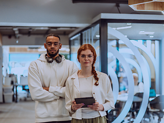 Image showing In a modern office African American young businessman and his businesswoman colleague, with her striking orange hair, engage in collaborative problem-solving sessions