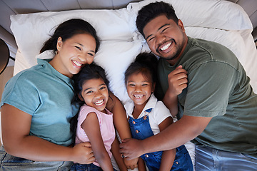 Image showing A happy black family in bed, mom and dad hold children with love. In their bedroom at home, little kids laugh as parents hug them with a smile on their faces and enjoy the quality time home together