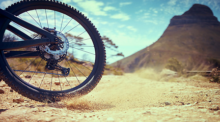 Image showing Bike, sport and adventure with a bicycle wheel in the dirt for adventure, risk or freedom and a mountain in the background. Bicycle, track and sports with a tyre turning in the sand for fun and speed