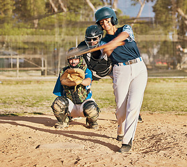 Image showing Baseball player, female athlete and swinging bat with sports technique or skill while playing a competitive game or match on a pitch or field. Fit female with a catcher doing exercise and recreation