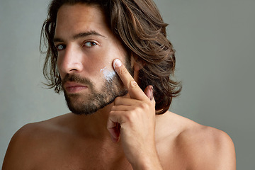 Image showing Portrait, facial or lotion with a shirtless man in studio on a gray background for his grooming routine. Skincare, face and beauty with the body of a young person with antiaging cream for his skin