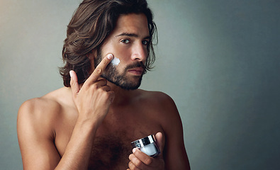 Image showing Portrait, skincare or lotion with a shirtless man in studio on a gray background for his grooming routine. Beauty, facial and and the body of a handsome young person with antiaging cream for his skin