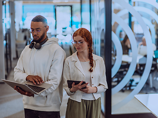 Image showing In a modern office African American young businessman and his businesswoman colleague, with her striking orange hair, engage in collaborative problem-solving sessions