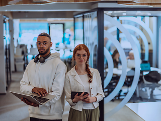 Image showing In a modern office African American young businessman and his businesswoman colleague, with her striking orange hair, engage in collaborative problem-solving sessions