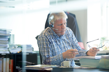 Image showing Senior, man and headset for consultant in office with career in telecom, customer care or support. Male financial advisor, talking or advice with spectacles for document, consumer feedback or reviews