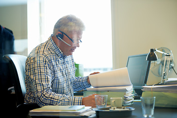 Image showing Senior businessman, documents and headphones in call center for communication or online advice at office. Mature man, consultant or agent reading paperwork for legal assistance or help at workplace