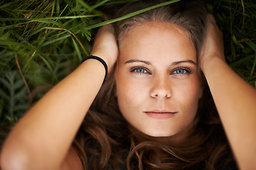 Image showing Portrait, above and beauty of woman on grass outdoor, healthy skin and freedom. Face, top view and young person in nature, green garden and serious attractive girl relax in summer in Switzerland.