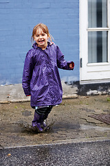 Image showing Child, portrait and splash in mud puddle in raincoat for winter fun, explore city or cold weather happy. Young girl, excited and water on holiday vacation break for wet game or joy, surprise as kid