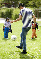 Image showing Kindergarten, teacher and playing football with children on grass, lawn or field with game or sport. Soccer, ball or kids with man training to kick or play on playground with fun exercise or activity