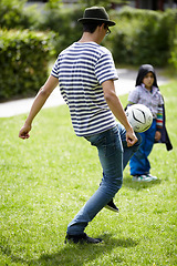 Image showing Man, playing football with child in garden on grass, lawn or field with game or sport. Soccer, ball or kid with person training to kick or play on playground with fun exercise or activity together