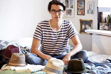 Image showing Fashion, hats and portrait of man in bedroom with fedora collection in home and apartment with nerd. Geek, style and person on bed with choice of vintage hat with trendy glasses and planning outfit