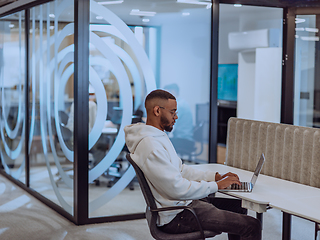Image showing In a modern office setting, an African American businessman is diligently working on his laptop, embodying determination, ambition, and productivity in his professional environmen