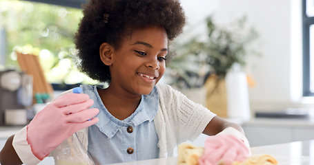 Image showing Child, gloves and happy in kitchen for cleaning, learning housekeeping as youth in home. Black girl, smile and cloth with sanitizer to shine counter and disinfectant surface in house with detergent