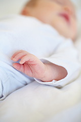 Image showing Closeup, baby or new born with hand on bed for love, caring and support in home. Infant, hope and milestone for future, growth or child development with trust for bonding, protection and security