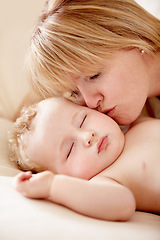Image showing Family, love and a mother kissing her baby closeup on a bed in their home for bonding together. Face, sleeping and an infant child in the bedroom of an apartment with his woman parent for affection