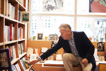 Image showing Reading, books and senior man in library for literature, information and knowledge in bookstore. Bookshelf, shopping and mature person with choice, decision and option for story, novel and learning