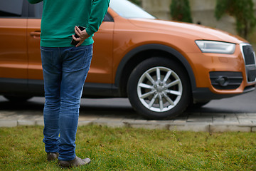 Image showing man taking photos on a smartphone of a car preparing for sale