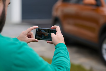 Image showing man taking photos on a smartphone of a car preparing for sale