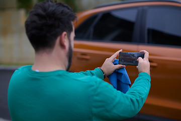 Image showing man taking photos on a smartphone of a car preparing for sale