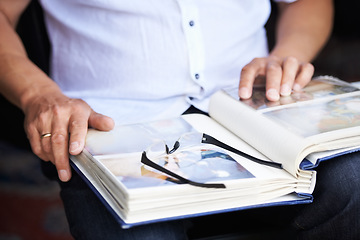 Image showing Photo album, photograph and hands of person for memory, reflection and nostalgia in home. Family pictures, glasses and closeup of photos in book to remember past, childhood and memories of youth