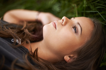 Image showing Face, thinking and relax with a woman on grass outdoor in a field closeup for daydreaming in summer. Peace, freedom and mind with a young person lying in a park for mental health, zen or awareness