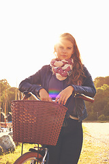 Image showing Portrait, summer and a girl with her bicycle in the park for travel, freedom or eco friendly adventure. Flare, cycling and a young person outdoor in the countryside for a cycling ride to relax