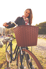 Image showing Portrait, flare and a girl with her bicycle in the park for travel, freedom or eco friendly adventure. Summer, cycling and a young person outdoor in the countryside for a cycling ride with a basket