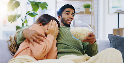 Image showing Fear, jump and couple watching tv on a sofa with popcorn for movie, film or streaming show at home. Omg, television and people hug in living room with cinema snack for scary, horror or spooky series