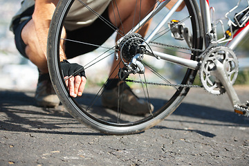 Image showing Check, wheel and hand on bicycle with road, street and outdoor exercise with flat tire. Cycling, athlete and closeup on safety, inspection and test for bike with person on asphalt with pedal or gears