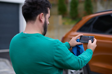 Image showing man taking photos on a smartphone of a car preparing for sale