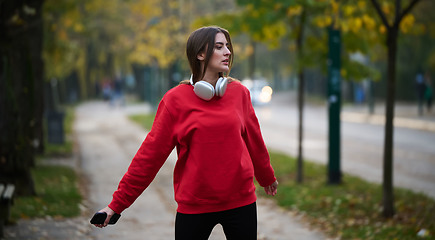 Image showing Athletic young woman taking a breath and relaxing after jogging and stretching. Woman Training and Workout Exercises On Street.