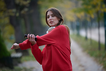 Image showing Athletic young woman taking a breath and relaxing after jogging and stretching. Woman Training and Workout Exercises On Street.