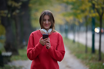 Image showing Sporty woman checks smartphone before doing some exercises listens music from a playlist