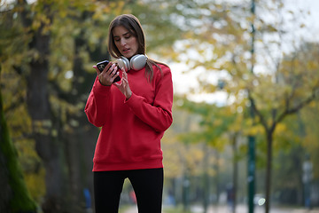 Image showing Sporty woman checks smartphone before doing some exercises listens music from a playlist