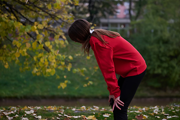 Image showing Athletic young woman taking a breath and relaxing after jogging and stretching. Woman Training and Workout Exercises On Street.