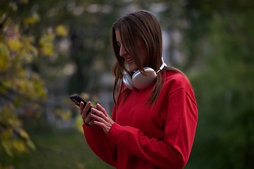 Image showing Sporty woman checks smartphone before doing some exercises listens music from a playlist